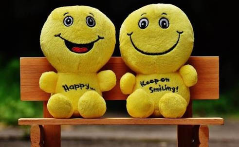 deux peluches jaune type smiley sur un banc