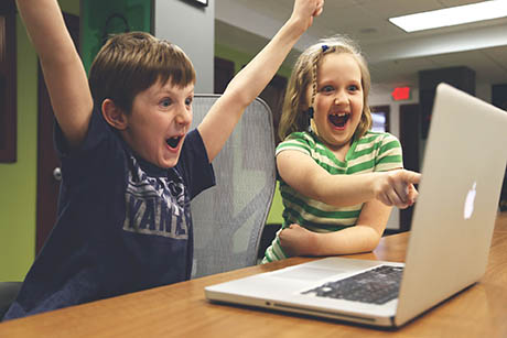 enfants sautant de joie devant un écran d'ordinateur